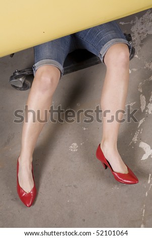 A woman wearing her fancy red heels having a problem with her car trying to fix it.