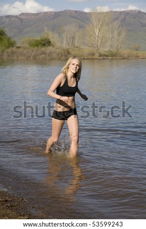 A woman running and cooling off in the water enjoying the refreshing feeling of the water.