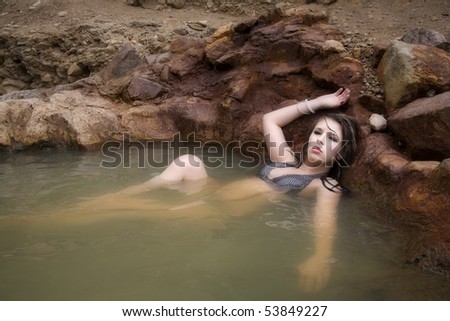 A woman is in the water with her hand over her head.