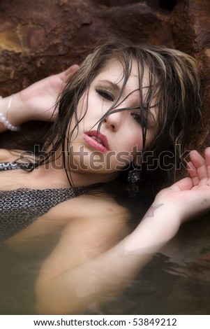 A woman in a swimsuit is looking serious through wet hair.