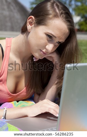 a woman working on her computer in the park with a sad expression on her face.