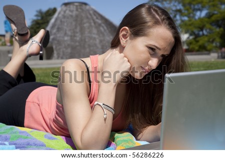 A woman concentrating on her work on the computer while she is in a park.