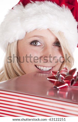 A female dressed like santa is peeking over the top of a present.