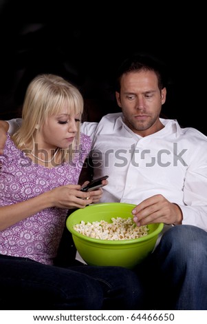 A man not too happy with his date texting  while they should be watching a movie together.