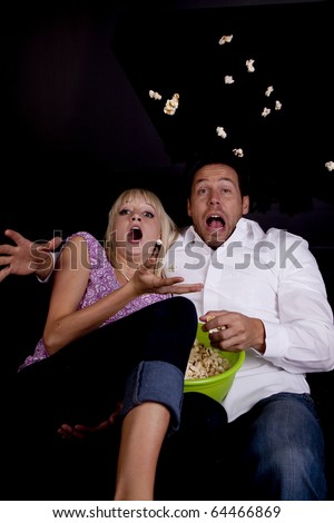 A couple watching a scary movie and it scared them so much that they threw the popcorn.