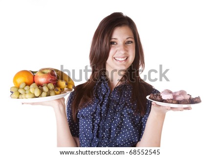 A woman is holding two plates while trying to decide which one to eat. One plate contains healthy fruits, while the other contains sweets.