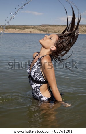 A woman flipping her wet hair making a rainbow of water with her hair.