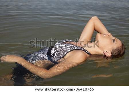 A woman laying her head back in the water getting her hair wet.