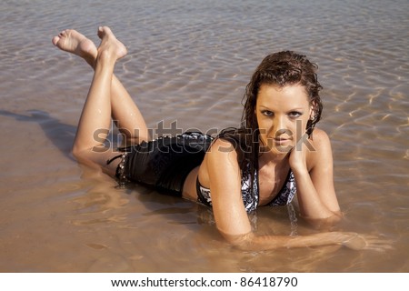 A woman laying in the water with a sexy expression on her face.