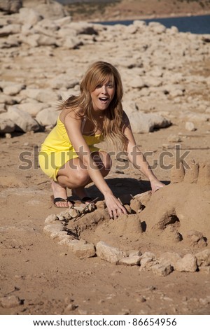 a woman having some fun building a huge sand castle.  She is shocked at how good it turned out.