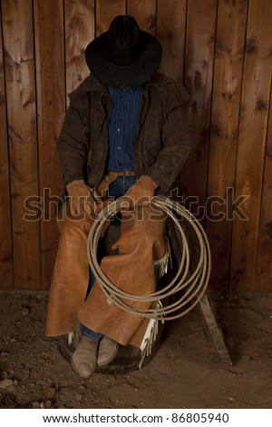 A cowboy sitting on a wine barrel with his head down.
