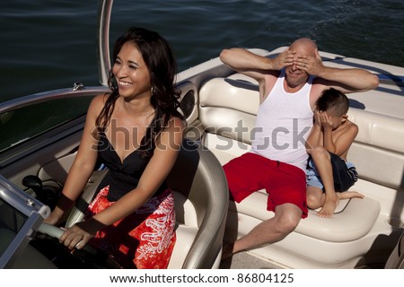 a mother is driving the boat her husband and son have their eyes covered because they are scared.