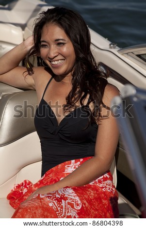 A woman sitting on the boat in her black suit and sarong with a smile on her face.