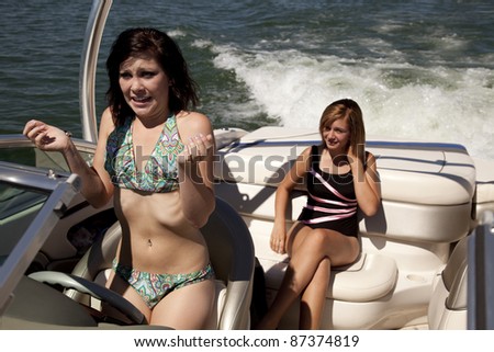 a woman driving her and her friend in a boat with a scared expression on her face.