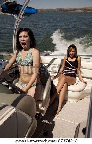 A woman driving a boat with her and her friend showing their scared expressions on their faces.