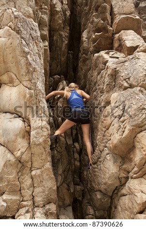 The back of a woman rock climbing up a mountain. - stock photo