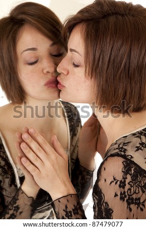 A woman kissing herself in the mirror.