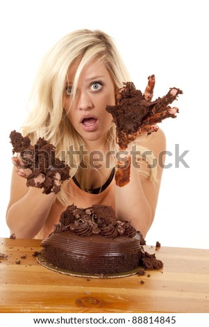a woman getting caught with her hands in the chocolate cake with a shocked expression on her face.