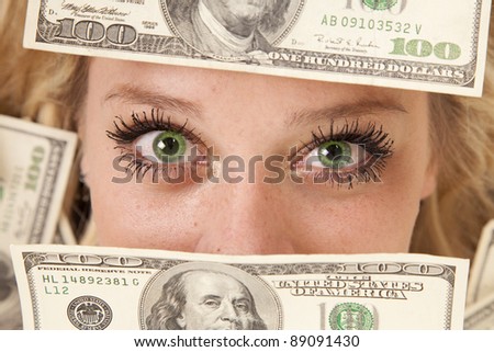 A woman with green eyes peeking through money