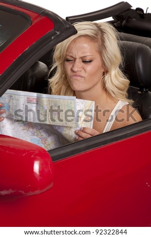 A woman sitting in her car with a frustrated expression on her face looking down at a road map.