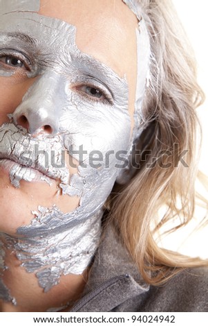 a woman\'s face with some of the siver paint off coming out of hiding.
