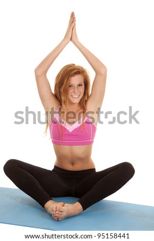 A woman sitting on her mat in a yoga pose with a smile on her face.