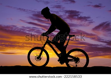 A silhouette of a man riding on a trail with his bike.