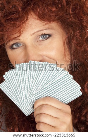A woman with a smile in her eyes holding on to her cards.