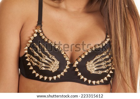 A woman in her black bra with gold spikes and skeleton hands.