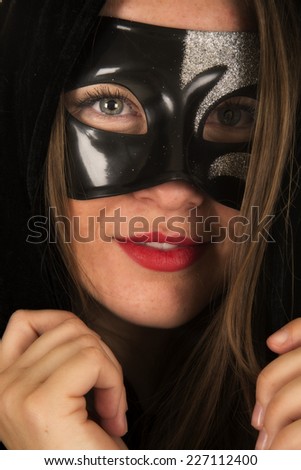 A close up of a woman in her black cloak and a mask.