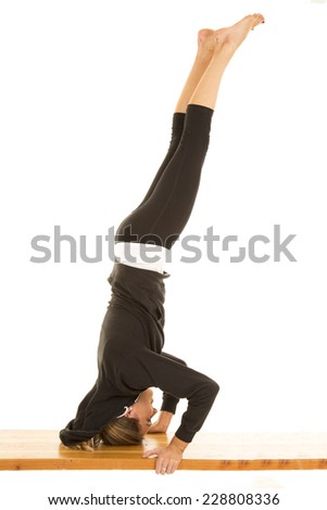 a woman doing a hand stand on a bench with her legs up in the air.