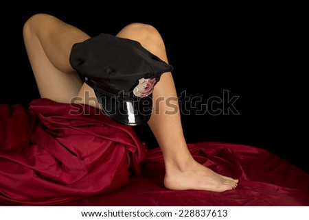 a woman laying in bed with a police hat on her foot.