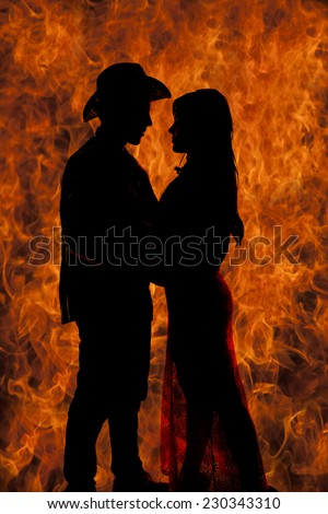 a silhouette of a western couple getting close, with a fire background.