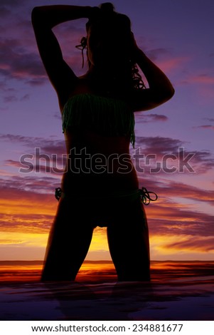 A silhouette of a woman kneeling down with her hands in her hair.