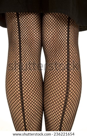 A close up of a woman legs in a black skirt wearing fishnet stockings.