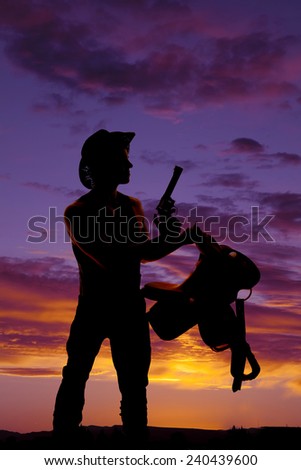 a silhouette of a cowboy holding on to his saddle holding on to his weapon.