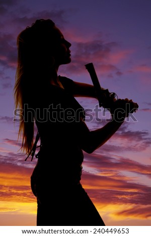 a silhouette of a woman with a pistol in her hand up by her lips.