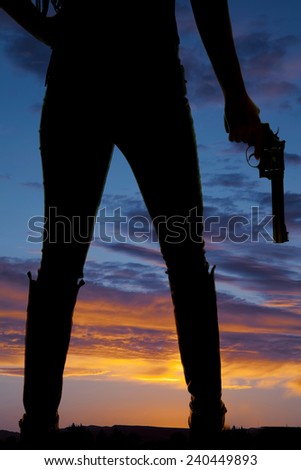 a silhouette of a woman\'s legs, she is holding on to a pistol to her side.