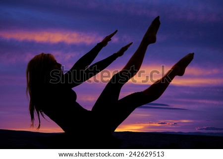 a silhouette of a woman doing a yoga ab workout with her legs up.