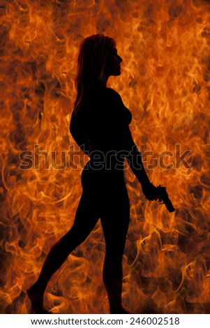 a silhouette of a woman in front of a fire, flame background holding a weapon in her hand.
