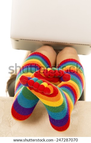 a woman with her colorful socks on and up, with a laptop on her knees
