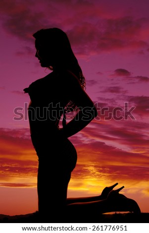 A silhouette of a woman kneeling down in her swimsuit.