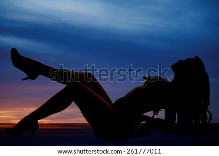 a silhouette of a woman laying back with her chest and legs up.