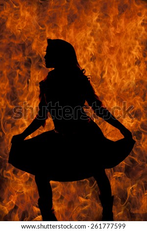 a silhouette of a woman holding out her skirt with flames in the background.