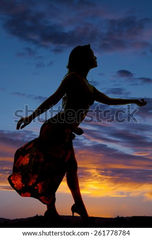 A silhouette of a woman in her sarong reaching out and dancing.