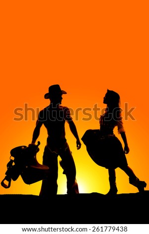 a silhouette of a cowgirl getting close to her cowboy, who is holding on to his saddle.
