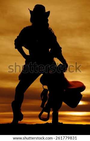 a silhouette of a woman in her western wear, holding on to her saddle