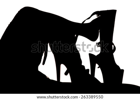 a silhouette of a woman\'s legs kicked up with her high heeled shoes next to her.