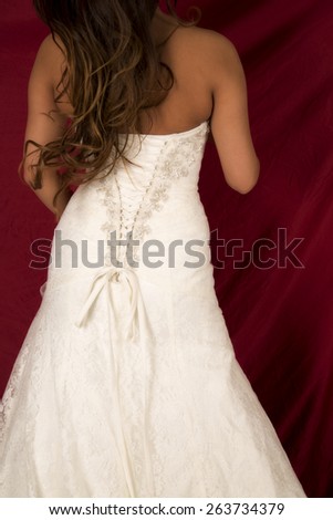 a woman in her wedding dress with her back to the camera showing off her buttons.