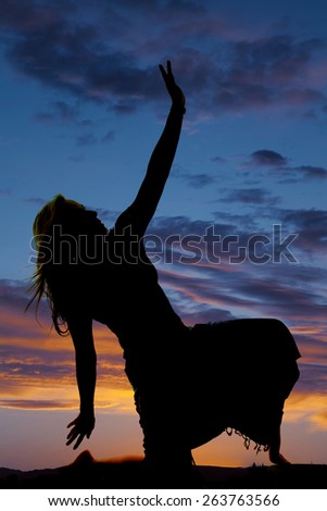 A silhouette of a woman kneeling in her skirt posing.